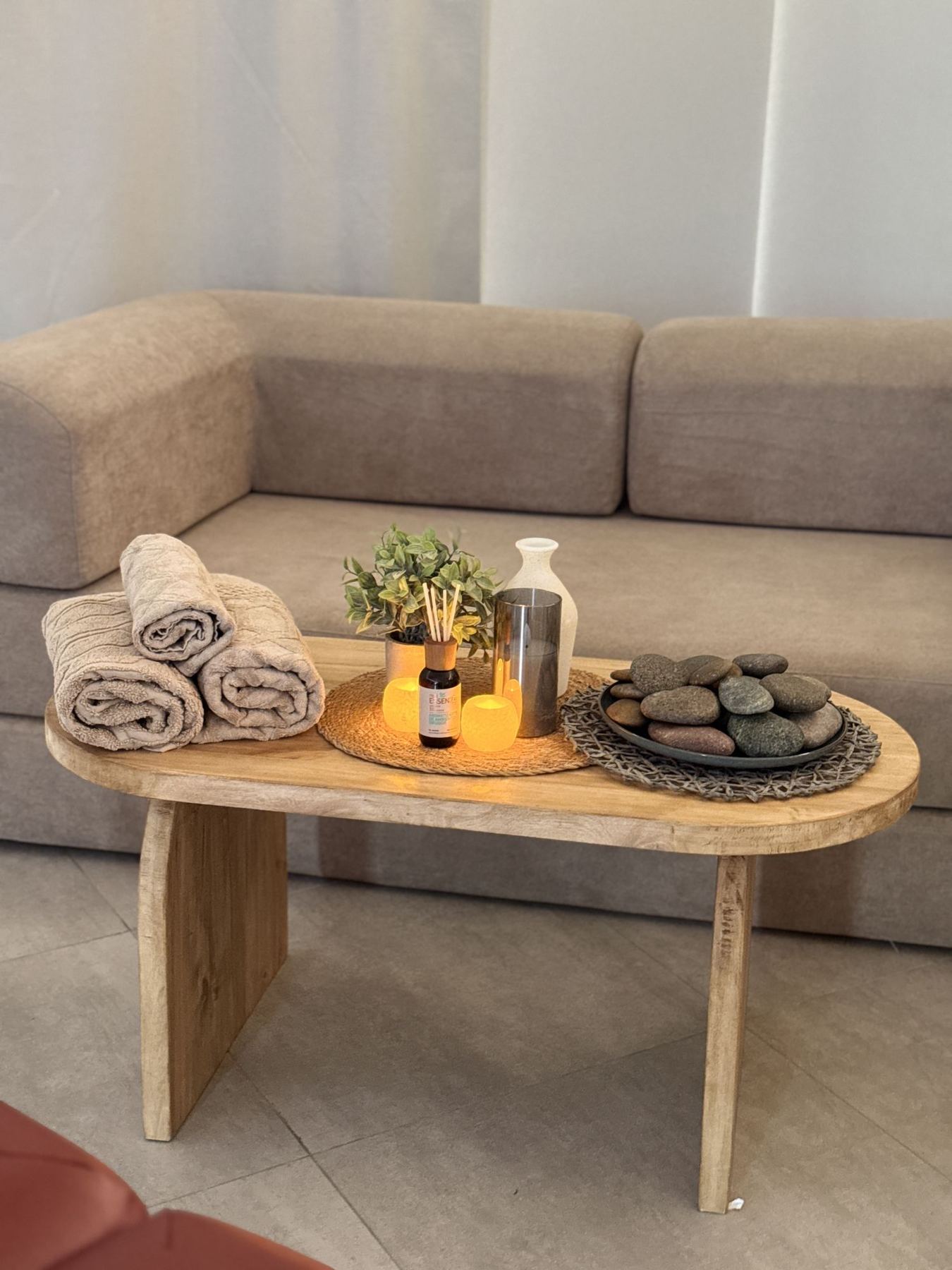 Toallas, velas, piedras y difusor sobre la mesa de apoyo