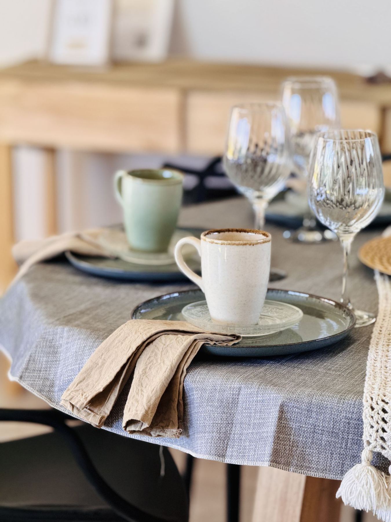 Mesa servida con platos de cerámica salvia, copas y servilletas de lino