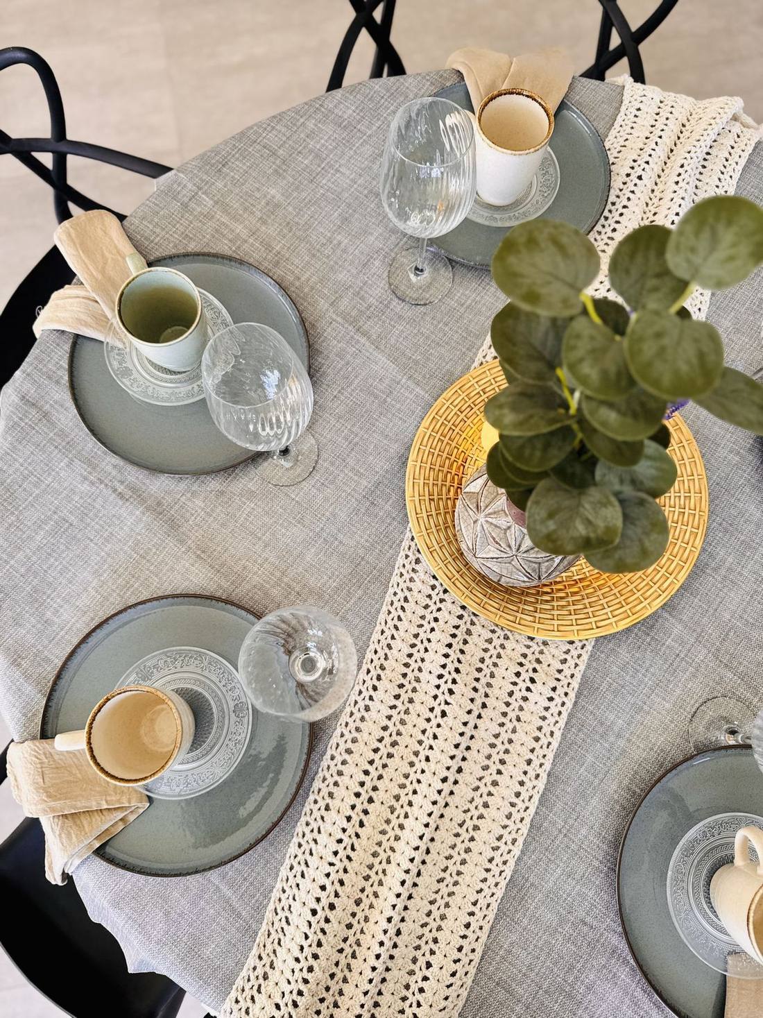 Vista cenital de la mesa: platos salvia, copas, tazas y camino de macramé